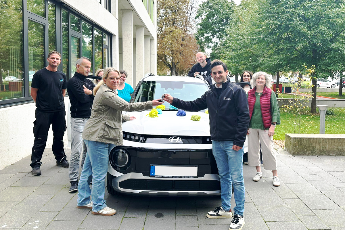 Auf dem Foto zu sehen ist Verkaufsberater Dario Zambuto bei der Übergabe der Hyundai INSTER an Frau Appold und ihr Team