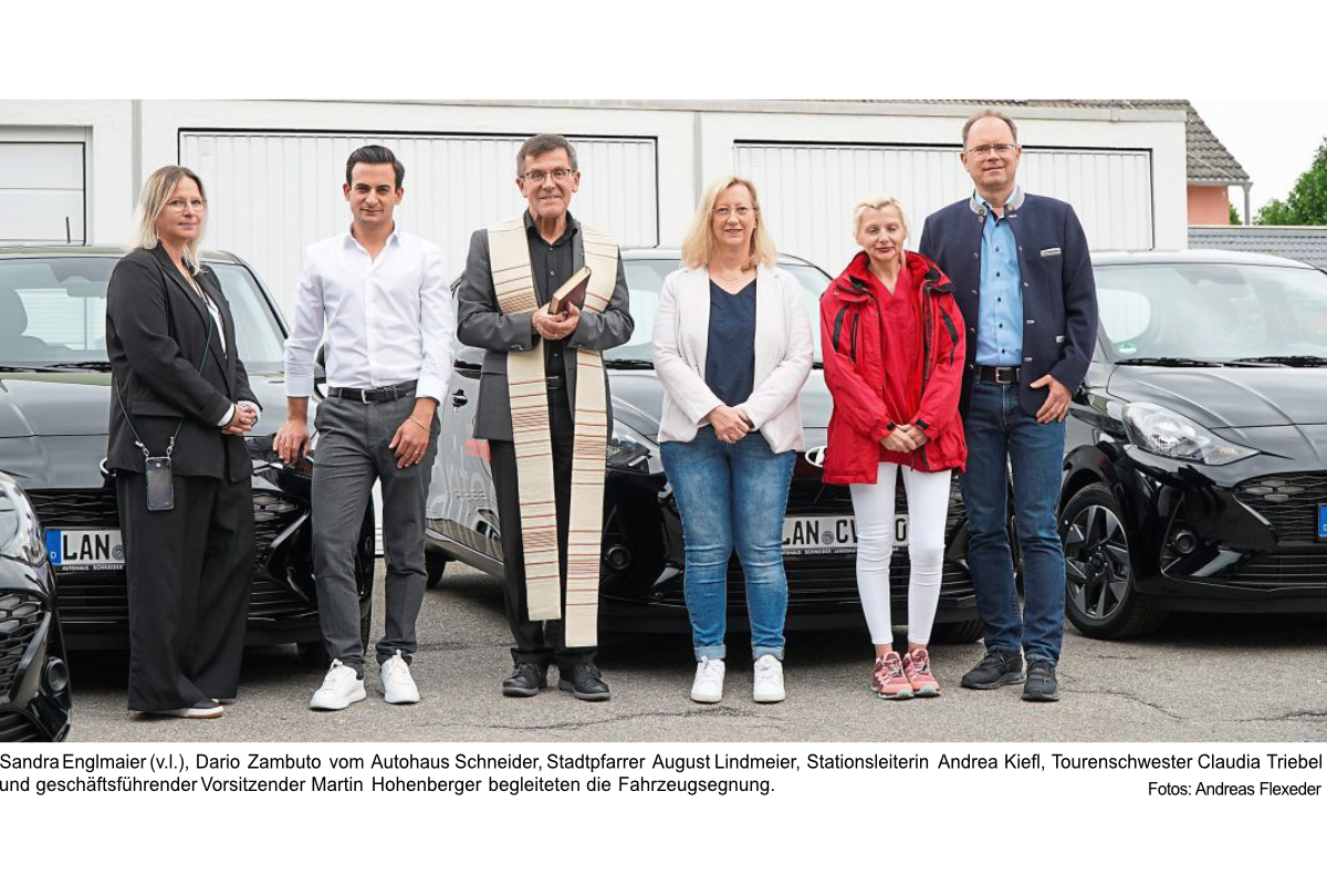 Sechs Personen bei der Fahrzeugübergabe und -segnung der Caritas Landau vor mehreren Autos.
