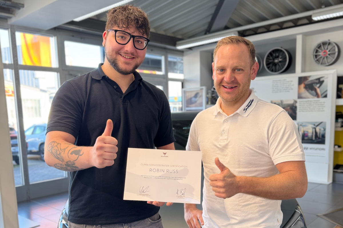 Zwei Männer halten ein Zertifikat und zeigen den Daumen nach oben