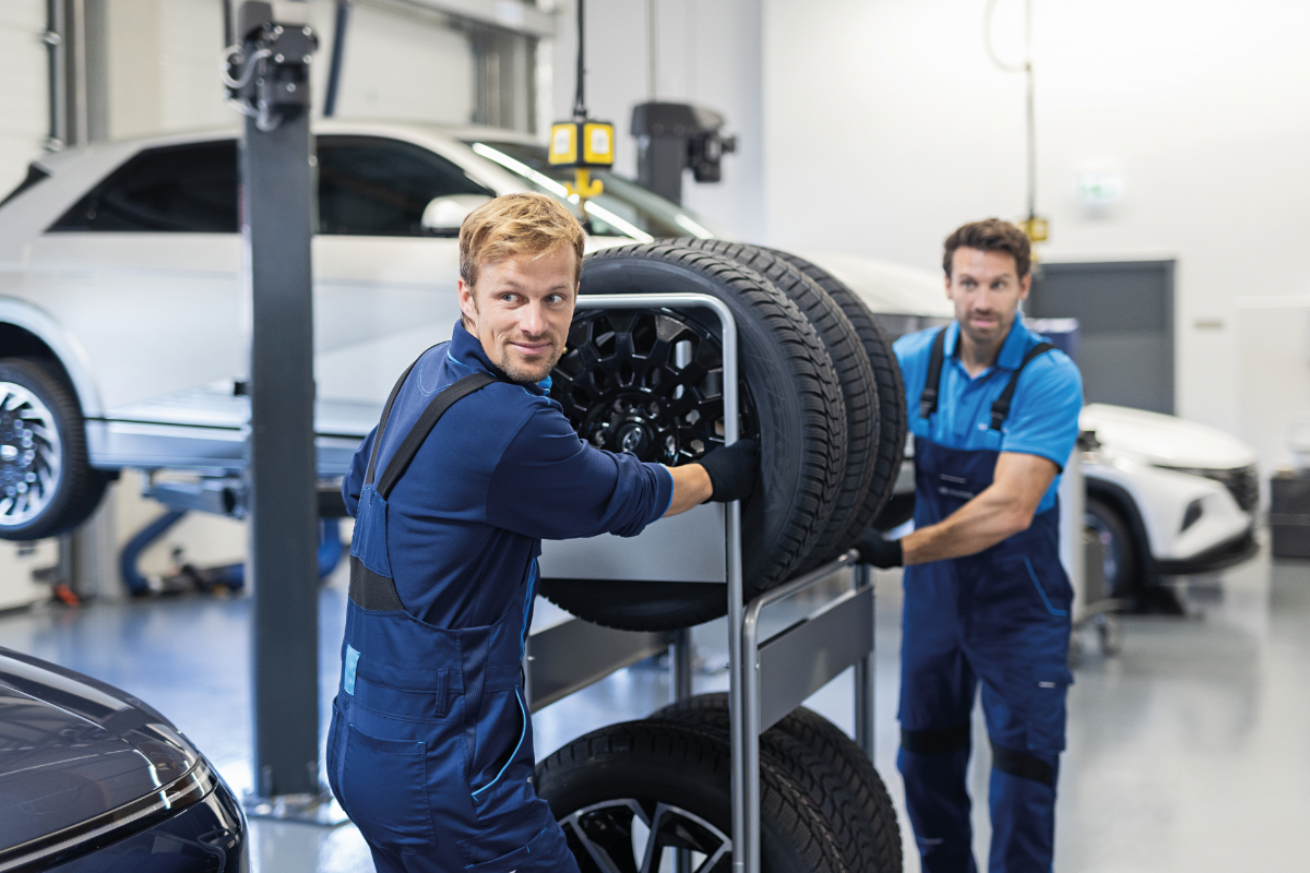 zwei Manner schiben ein Regal mit Reifen